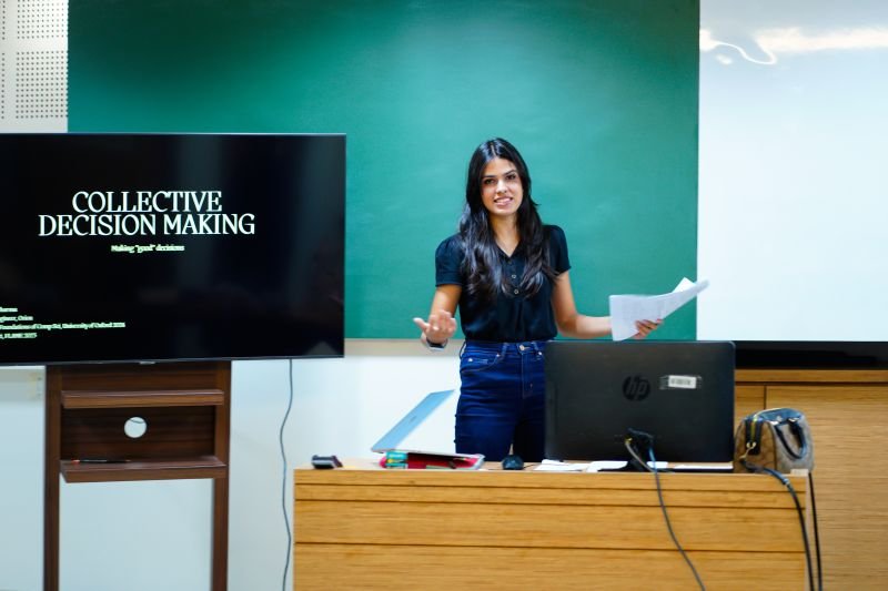 Presenting a guest lecture on collective decision making at FLAME University, beside a screen reading 'Collective Decision Making'