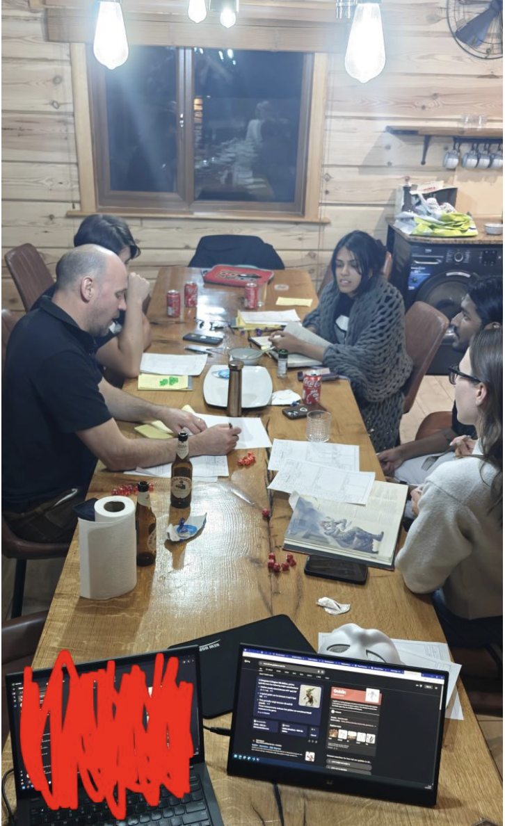 The Orion team mid-game around a long wooden table at a cabin retreat, character sheets and dice everywhere